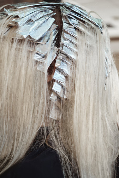 Sustainable hair foils: A young woman in a hairdressing salon dyes her hair blond. Hair coloring process