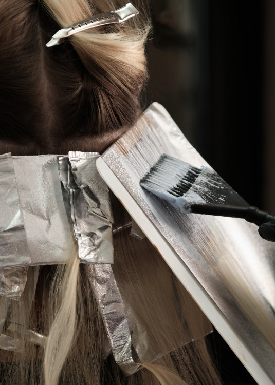 Sustainable hair foils: A young woman in a hairdressing salon dyes her hair blond. Hair coloring process